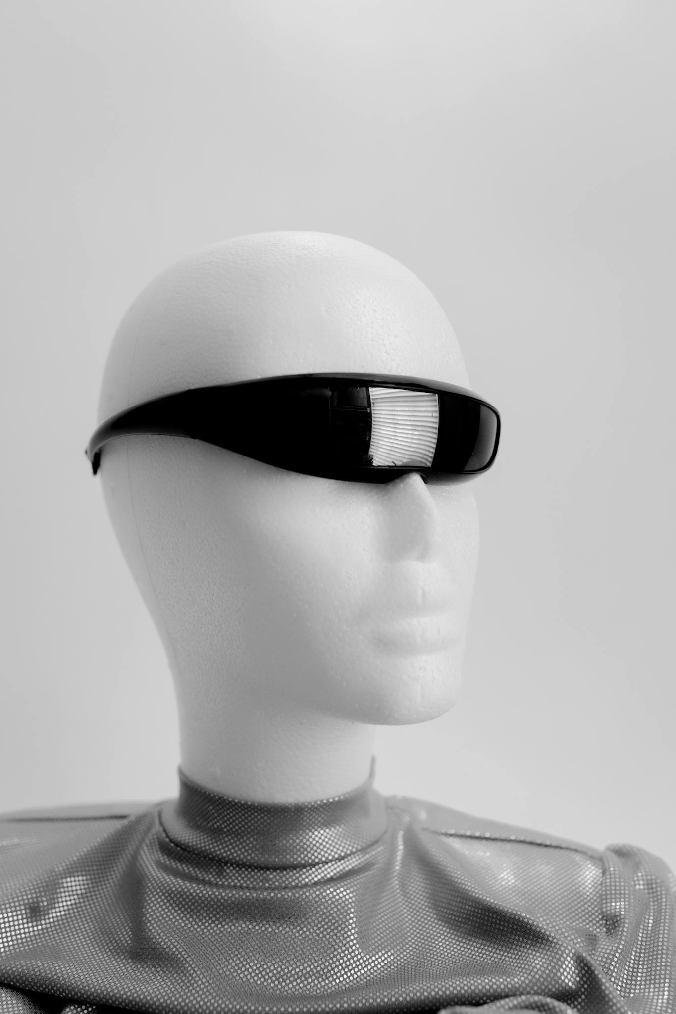 Minimalist image of a mannequin wearing futuristic sunglasses, showcasing a sci-fi vibe.